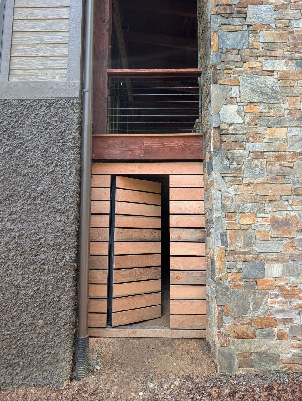 The same panel in raw, unstained wood, propped open against its frame before staining, hinge hardware visible on the inside edge.
