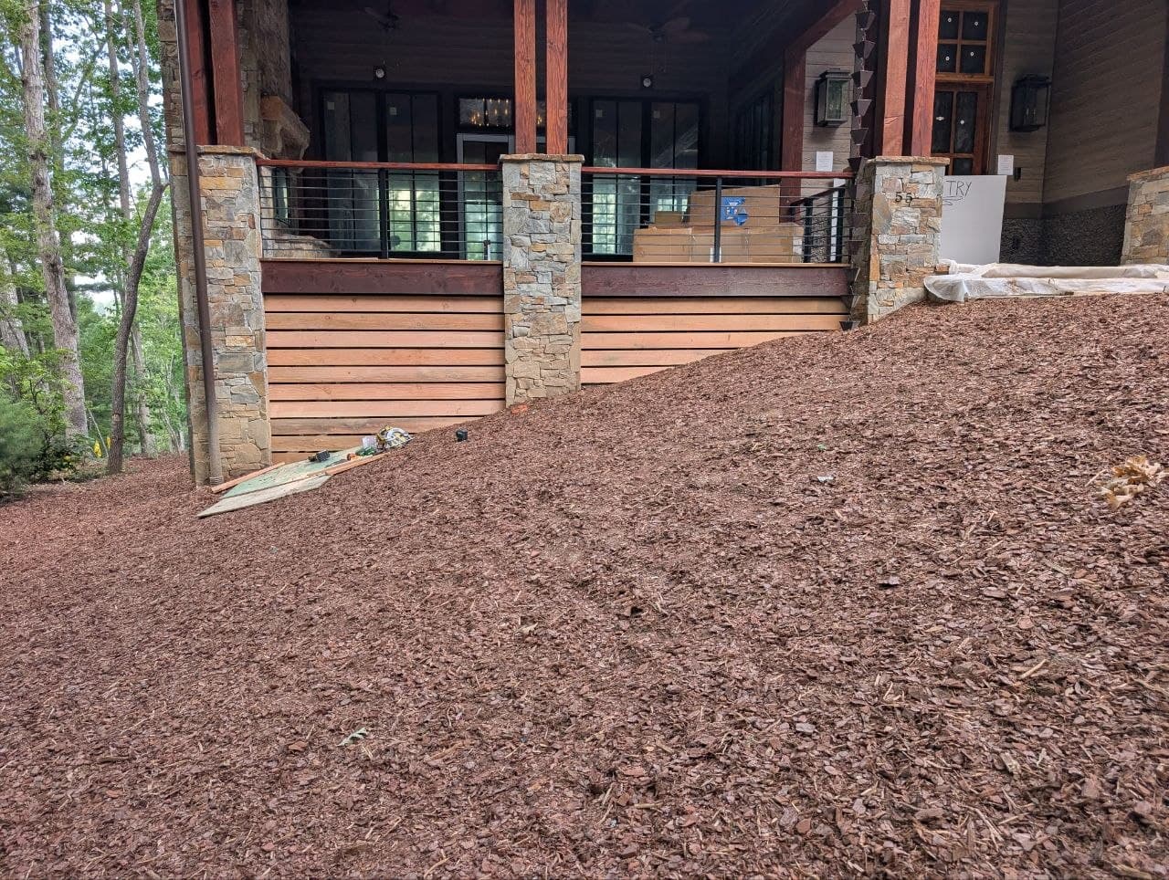 Covered deck with stone-clad support columns, steel cable railing and cedar skirting, stained tongue-and-groove ceiling above